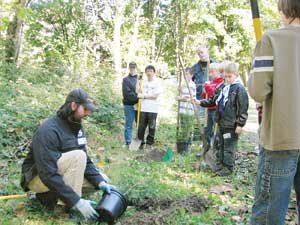 Aaron Milner, a certified arborist with the city, demonstrates how to plant a tree in May Creek Park last year. By Jim Feehan