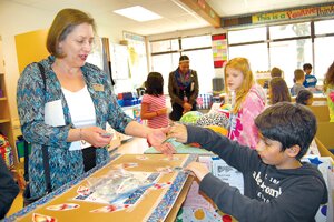 By Christina Corrales-Toy Anne Moore, Issaquah School Board member (left), makes a purchase from Rocket City merchant Ishan Misro during Apollo ’s Classroom City simulation.
