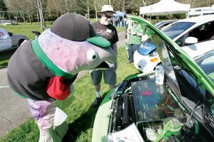 By Greg Farrar Bert the Salmon is glad to learn less motor oil will be polluting his habitat as he looks under the hood of an electric car owned by Jeff Finn of Bellevue.