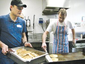File Richard Blakely (right) adds fresh pancakes for Jim Tintinger to deliver to volunteer servers at the annual Hazelwood pancake breakfast in 2012.